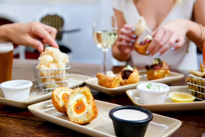Guests enjoy traditional British pub fare, including Scotch eggs and drinks, on a London food and drinks private tour.