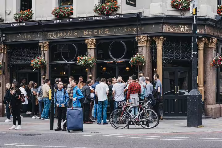 Crowd enjoying drinks outside a historic London pub on a private British tavern tour, showcasing lively city atmosphere.