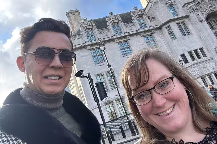 Two smiling tourists on a London Royal Walking Tour selfie in front of a grand historic building