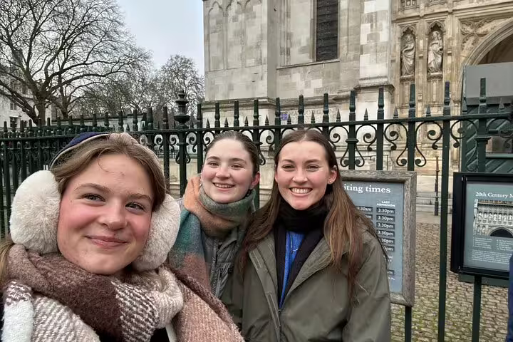 Three smiling women on a London Royal Walking Tour selfie outside Westminster Abbey gates