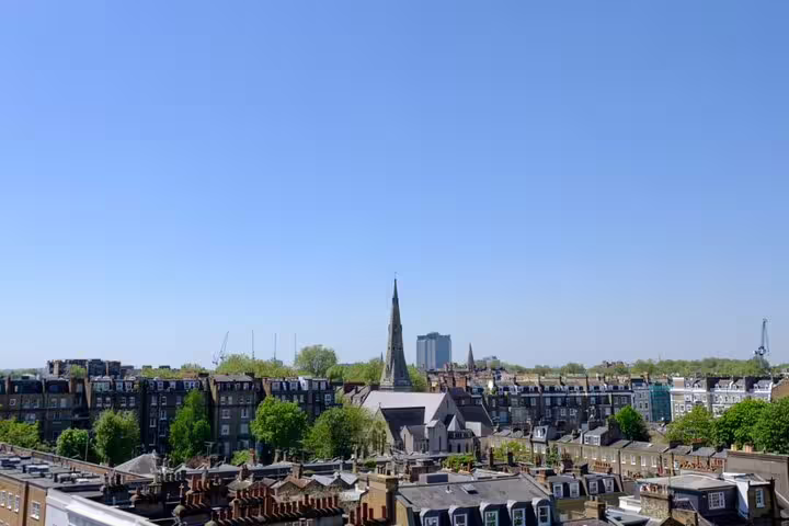 London rooftop skyline view with church spire and Victorian buildings on a clear blue sky day