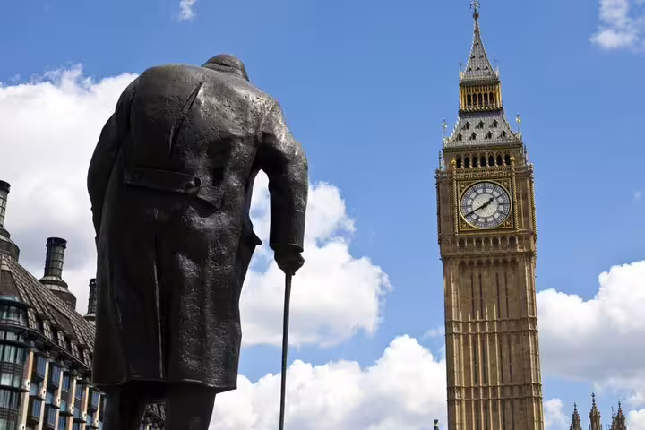 Bronze statue facing Big Ben clock tower in London on a sunny day