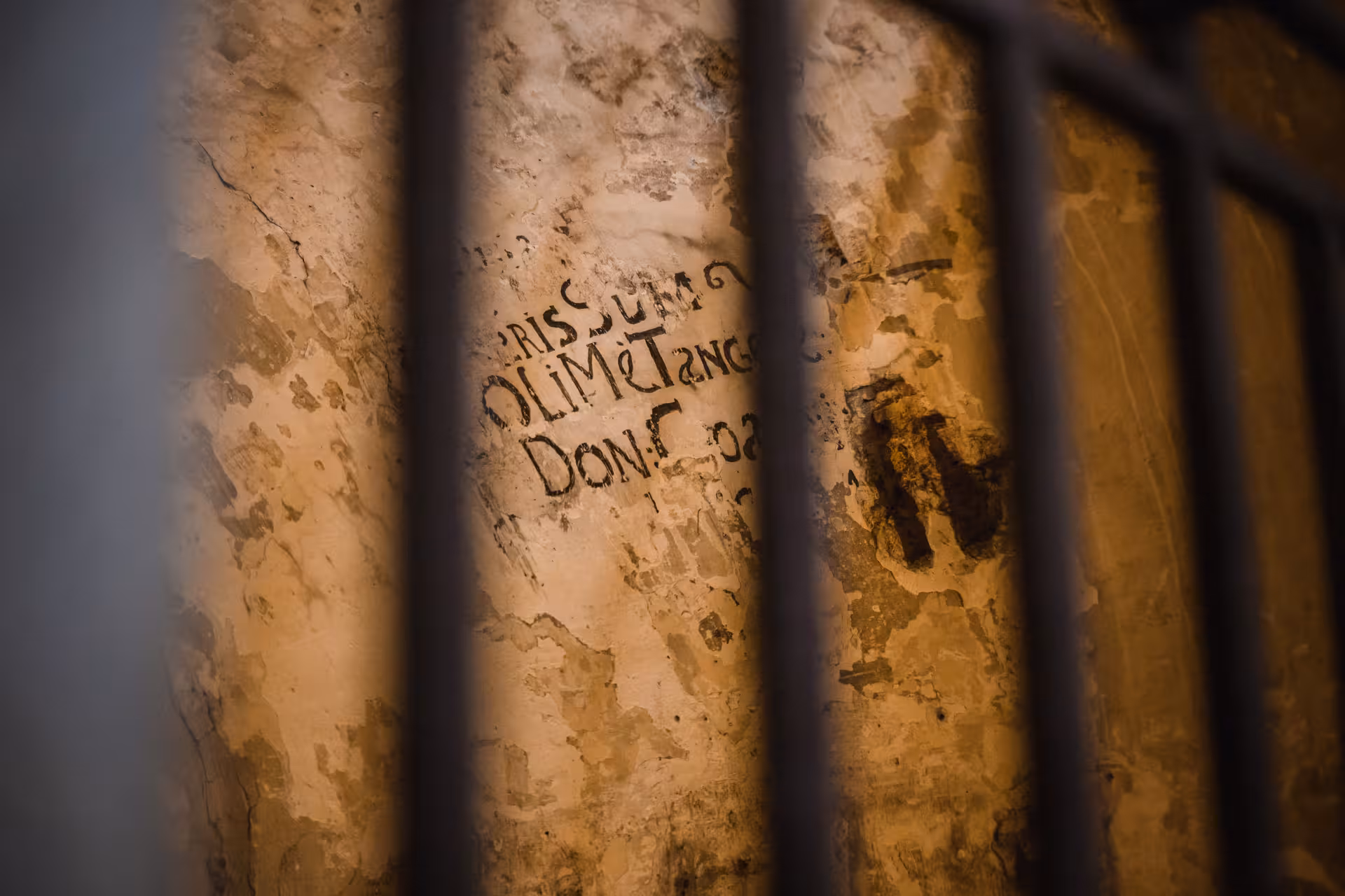 Close-up of ancient graffiti on prison wall at Lords of The Night, highlighting historical inscriptions and ambiance.