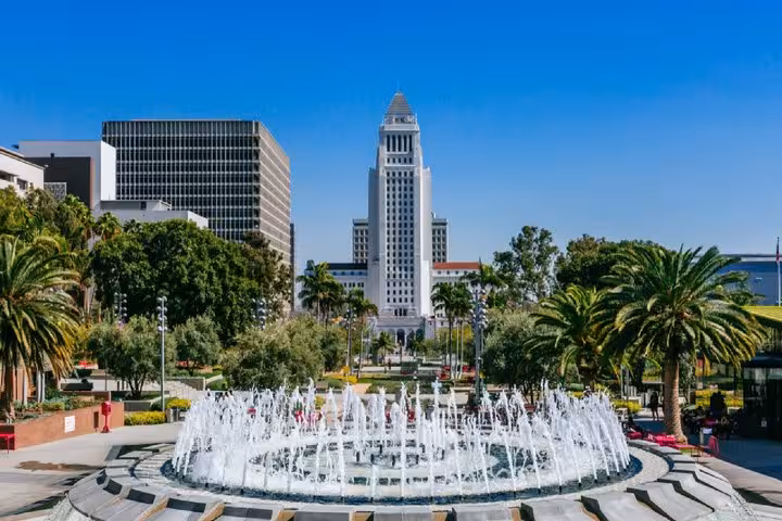 Los Angeles City Hall tower with Grand Park fountain and palm trees on a sunny day