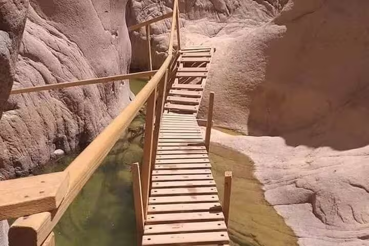 Wooden footbridge over clear canyon water at Lost Lake on private jeep safari from Sharm El Sheikh to Dahab