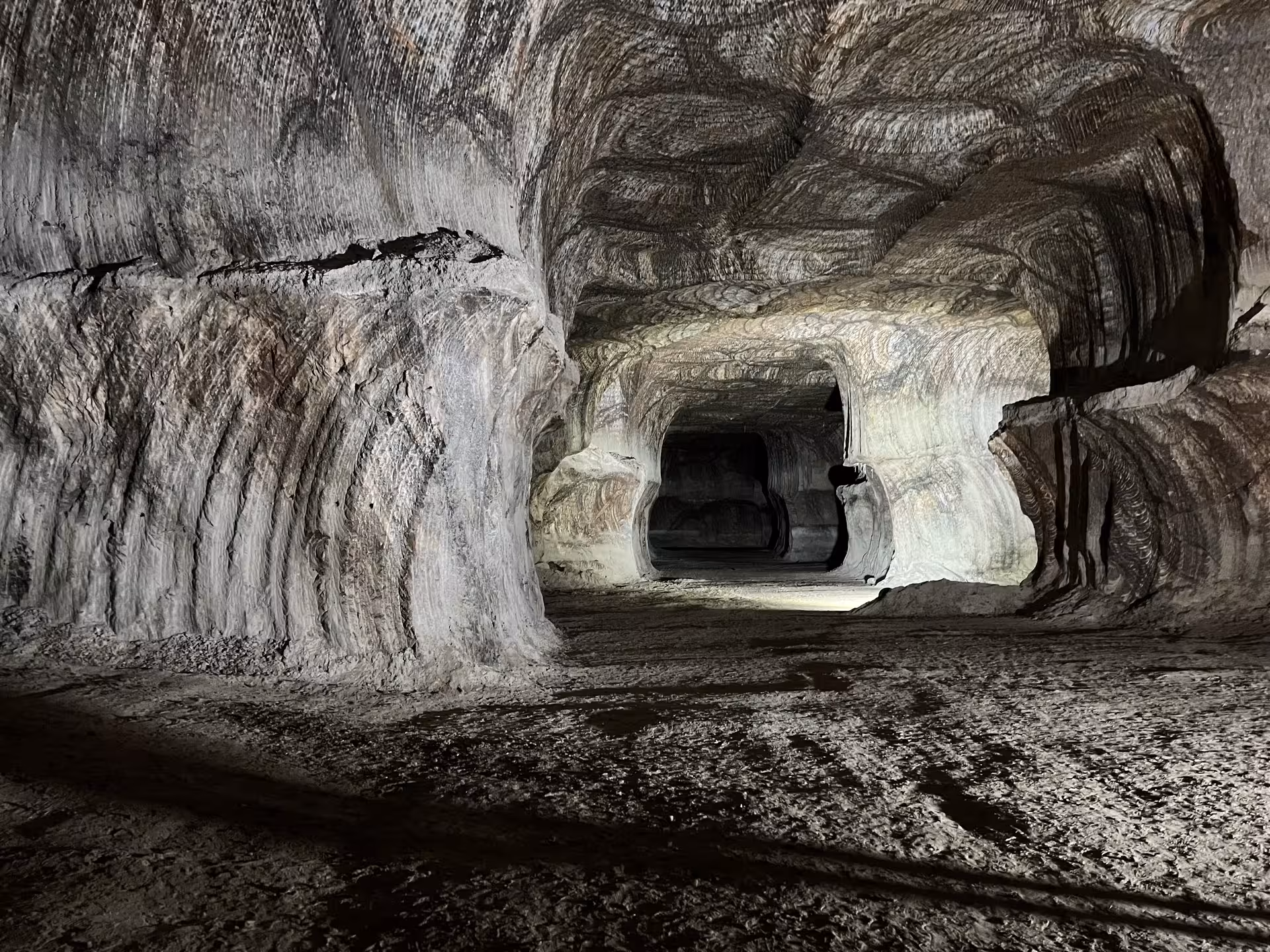 Expansive tunnel view in Loulé's rocksalt mine, showcasing layered salt patterns and natural cavern formations.