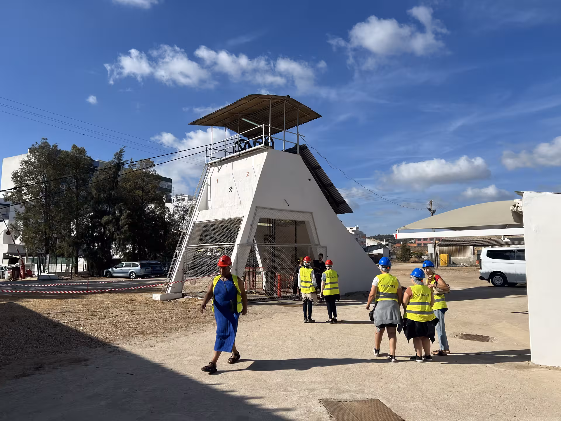 Visitors wearing safety gear approach the entrance of the Loulé rocksalt mine under a clear Algarve sky.
