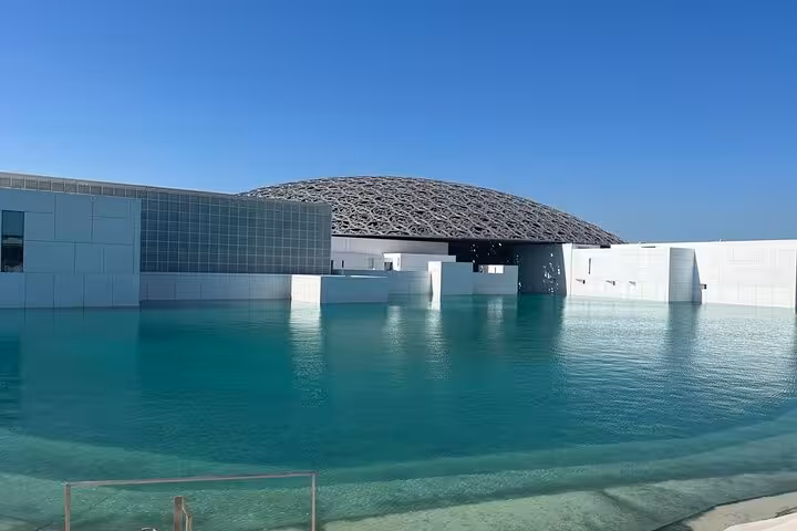 Iconic Louvre Abu Dhabi museum with turquoise water reflection on a full-day Abu Dhabi city tour