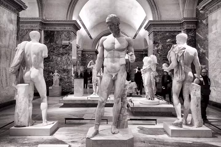 Classical Greek and Roman marble sculptures of male figures in grand Louvre museum gallery hall