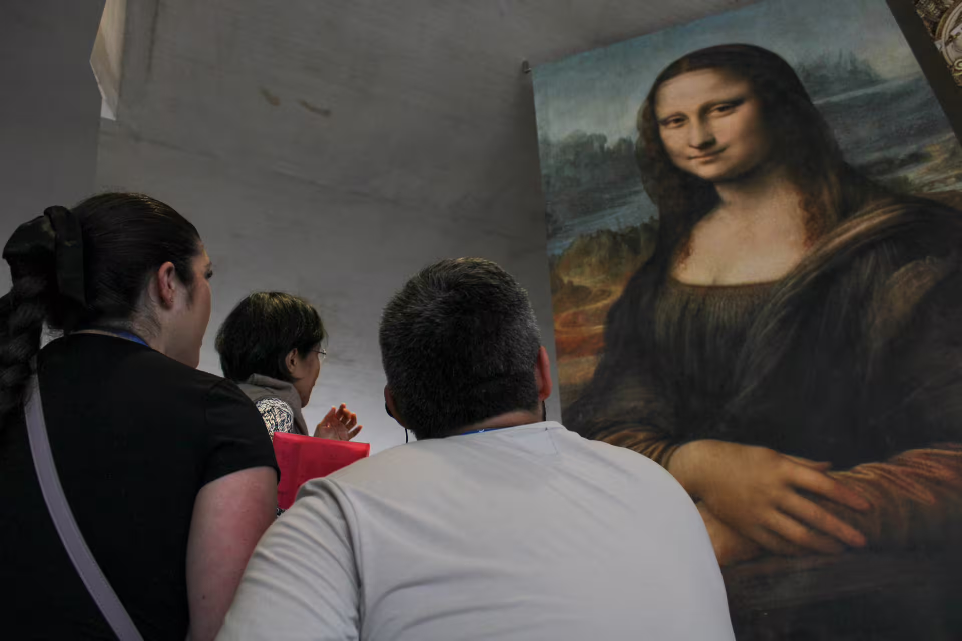 Visitors viewing a large Mona Lisa painting reproduction during a Louvre guided tour