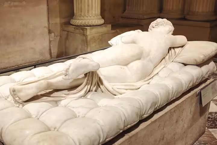 Marble sculpture of reclining figure on cushioned mattress at the Louvre Museum