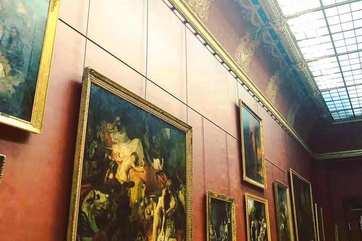 Grand gallery wall with large classical paintings in golden frames at the Louvre Museum, Paris