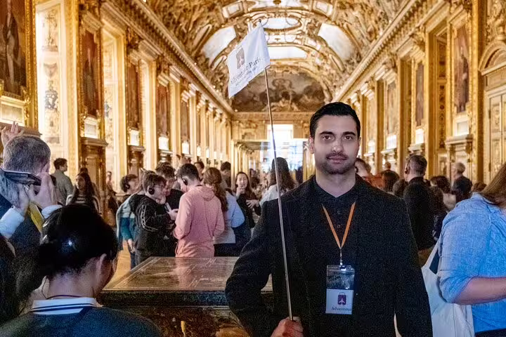 Tour guide leading a group inside the ornate halls of the Louvre Museum, showcasing the rich art and history.