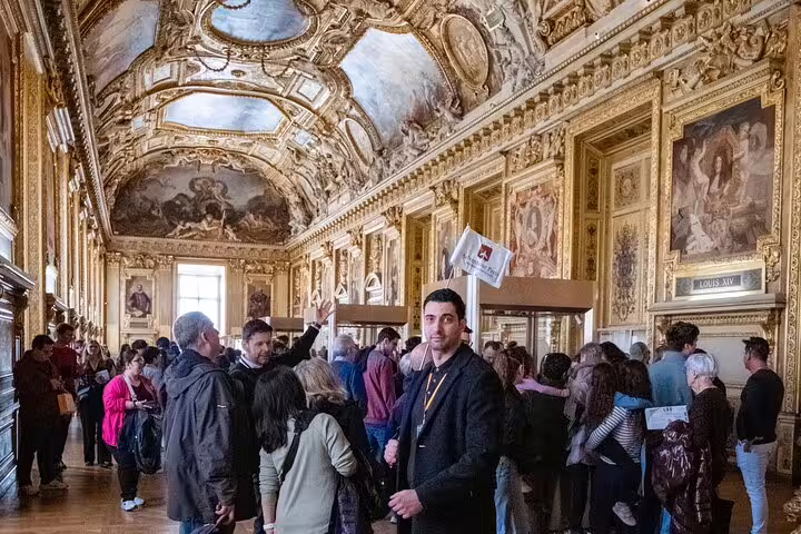 Experience the grandeur of the Louvre's opulent halls filled with art and visitors on an exclusive guided museum tour.