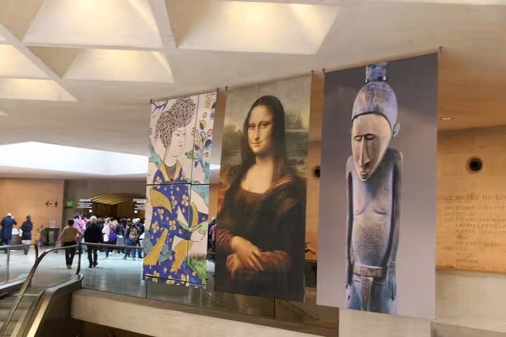 Mona Lisa and art banners hanging in the Louvre Museum entrance hall with visitors below