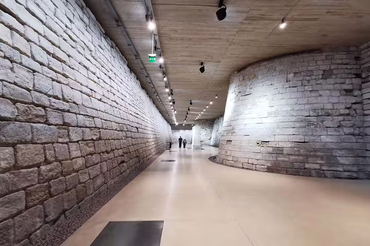 Stone-walled corridor in the Louvre Museum on a guided tour with skip-the-line tickets, Paris underground passage
