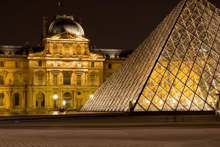 Louvre Museum glass pyramid illuminated at night during Paris panoramic guided tour
