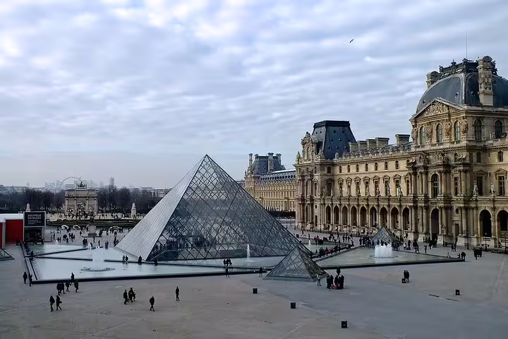 Louvre Museum glass pyramid courtyard with visitors and ornate palace facade in Paris