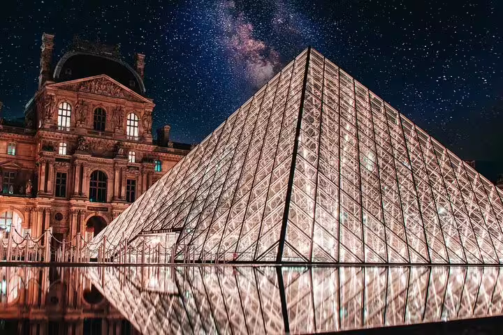 Louvre Pyramid illuminated at night under a starry sky in Paris