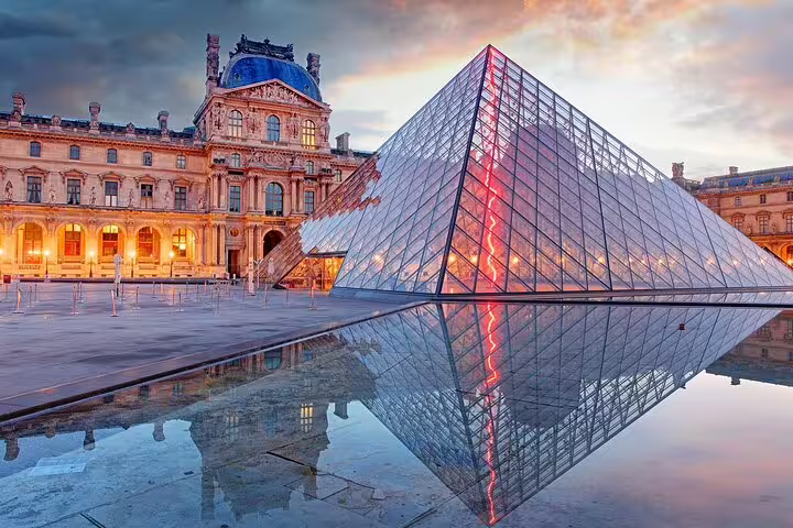 Louvre Museum glass pyramid reflecting in water at dusk, Paris