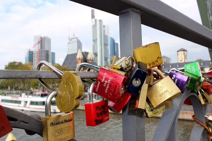 Colorful love locks on a bridge railing with Frankfurt skyline and river in the background