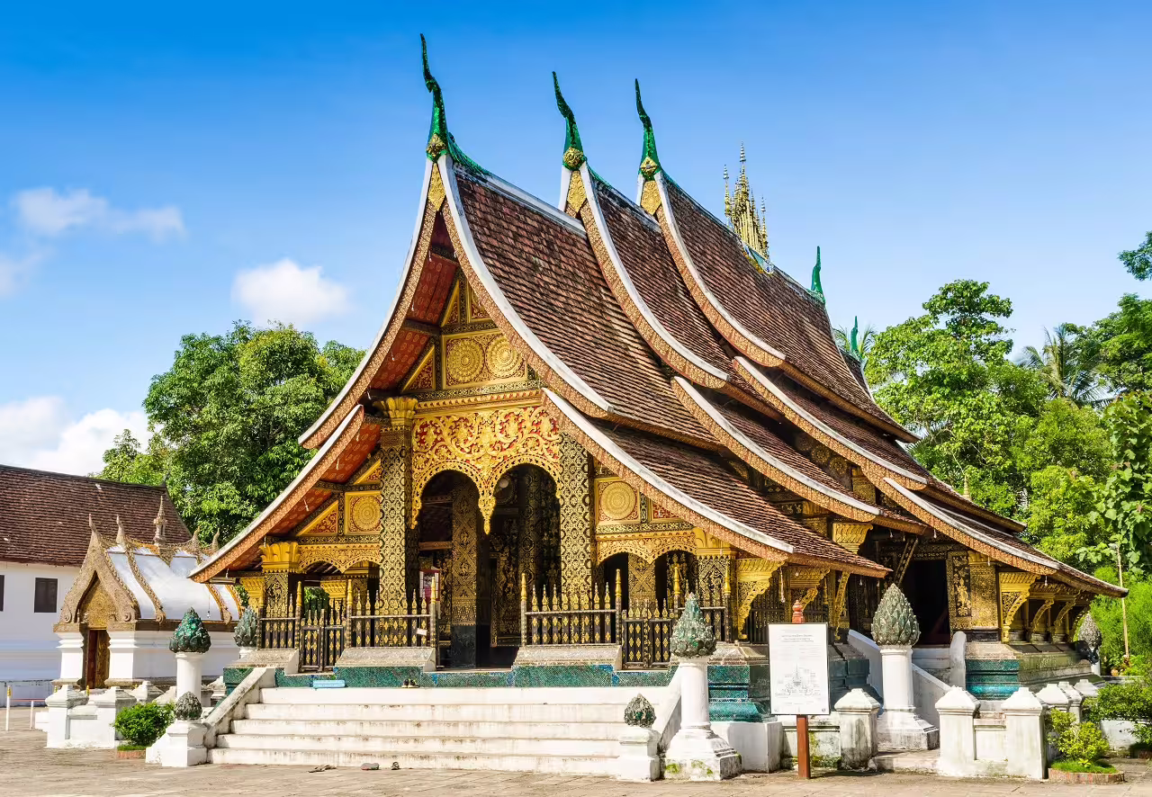 Ornate Buddhist temple with intricate carvings and tiered roofs in Luang Prabang, Laos.