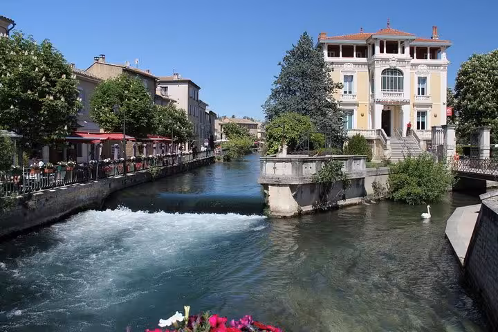 Canal in Luberon village with riverside cafés and pastel buildings on private day trip from Marseille port