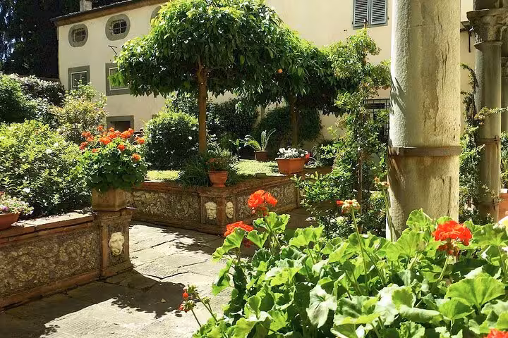 Charming garden courtyard in Lucca with vibrant flowers, ideal for relaxing on a sunny day.