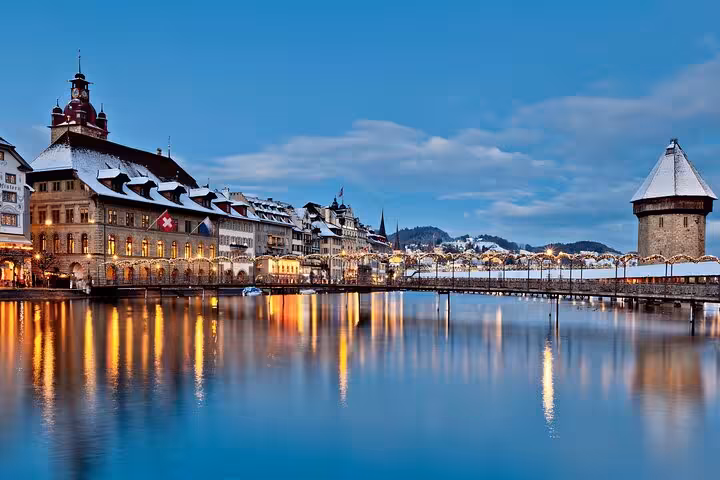 Evening view of Lucerne's historic architecture and Chapel Bridge reflecting on the Reuss River, perfect for a Swiss tour.