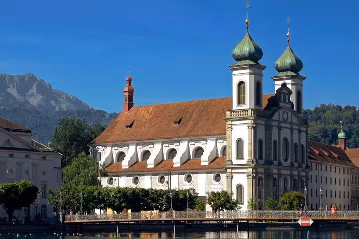 Jesuit Church baroque towers with green onion domes on the Reuss River in Lucerne, Switzerland