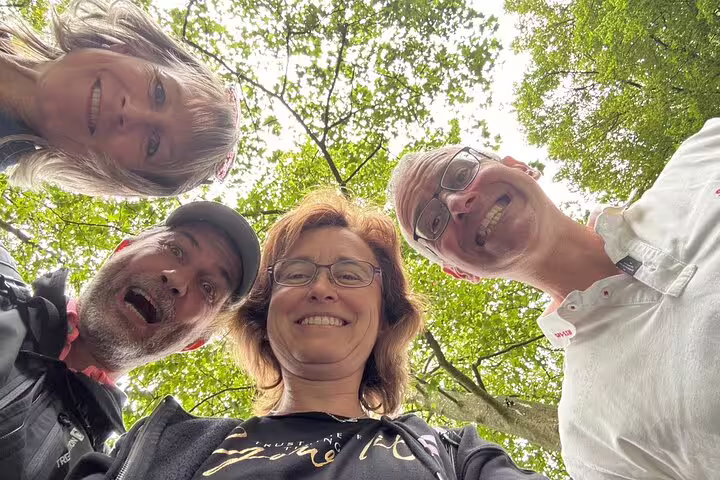 Smiling friends on a Lucerne self-guided scavenger hunt tour, looking up under leafy trees in Switzerland