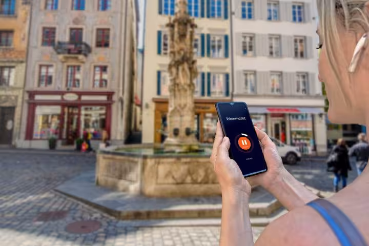 Tourist using audio guide app at Weinmarkt fountain square in Lucerne old town