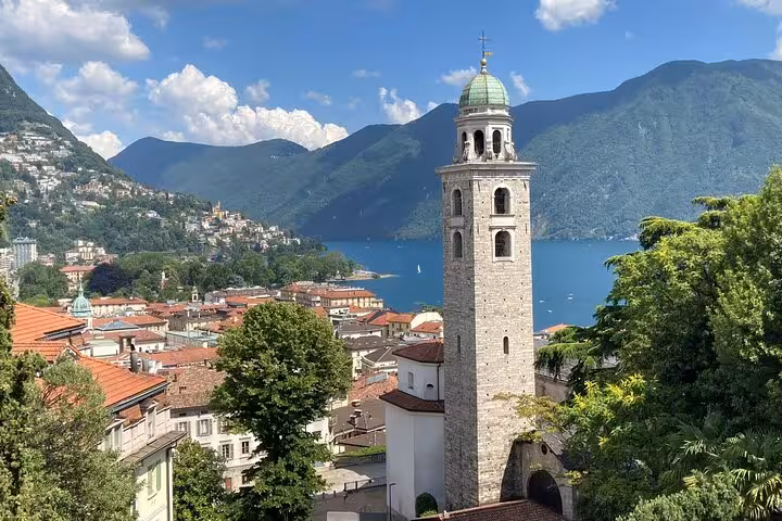 Lugano city tour view of San Lorenzo Cathedral bell tower above Lake Lugano and alpine mountains