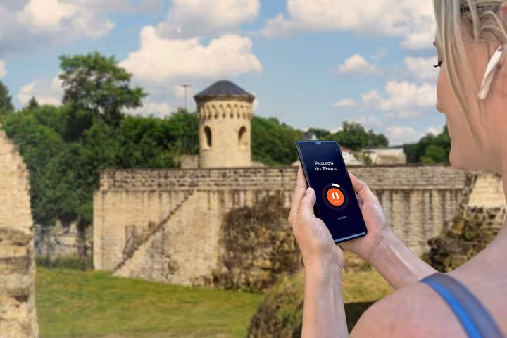 Tourist holding smartphone with audio guide app at Luxembourg City historic stone fortress walls