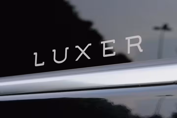 Close-up of Luxer logo on sleek black vehicle used for Ravenna to Venice transfers.