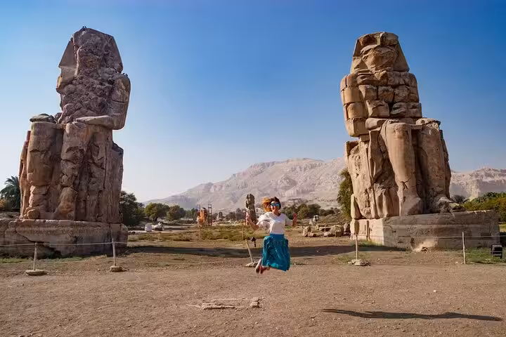 Tourist between Colossi of Memnon statues in Luxor on a private day tour with horse carriage ride and flexible plan