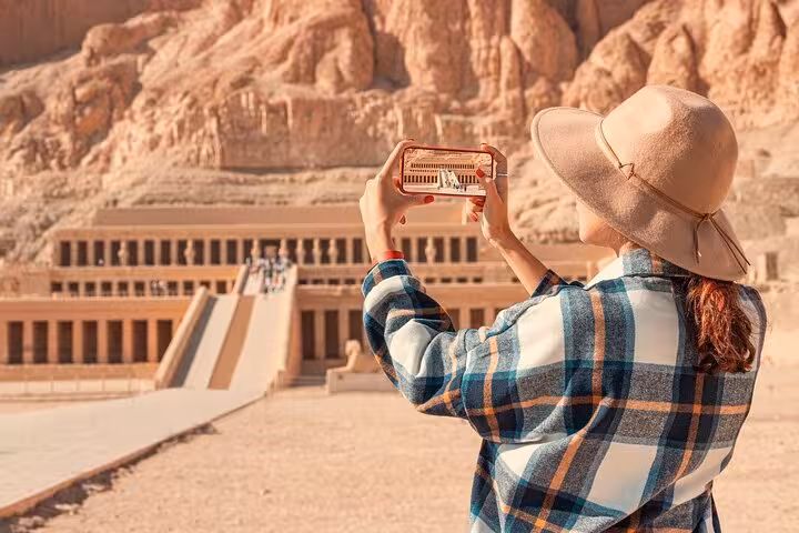 Tourist photographing Hatshepsut Temple in Luxor on a private day tour with flexible itinerary and horse carriage ride