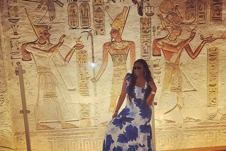 Traveler posing by colorful ancient Egyptian wall reliefs in Luxor, Hurghada day trip with hot air balloon ride
