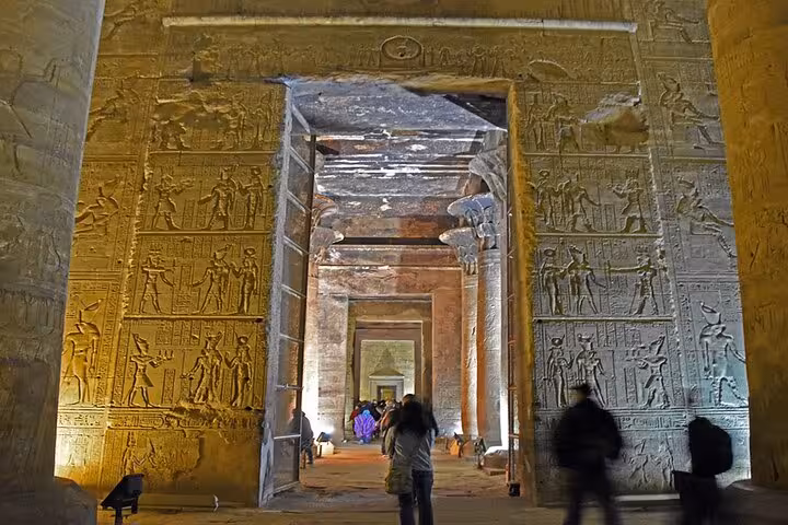 Guided Luxor East and West Bank tour inside Karnak Temple corridor with illuminated hieroglyphs