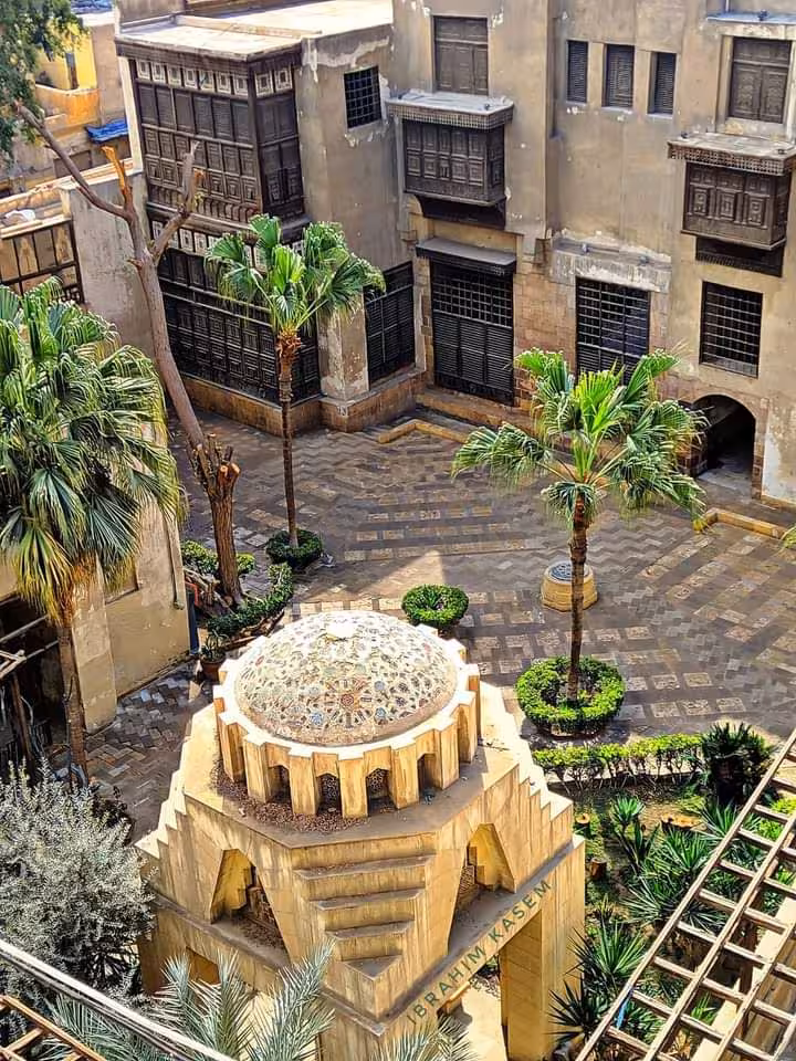 Historic courtyard in Luxor showcasing traditional architecture and lush palm trees, perfect for cultural exploration.