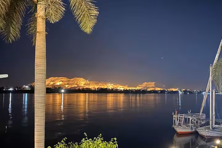 Night view of the Nile in Luxor with felucca boats and palm trees, seen on a private horse carriage ride