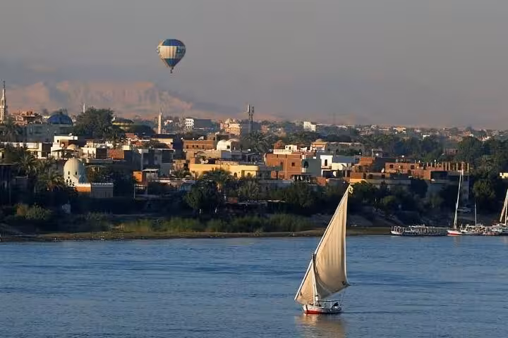 Felucca sailing on the Nile with Luxor skyline and hot air balloon overhead, VIP sunrise tour with hotel pickup