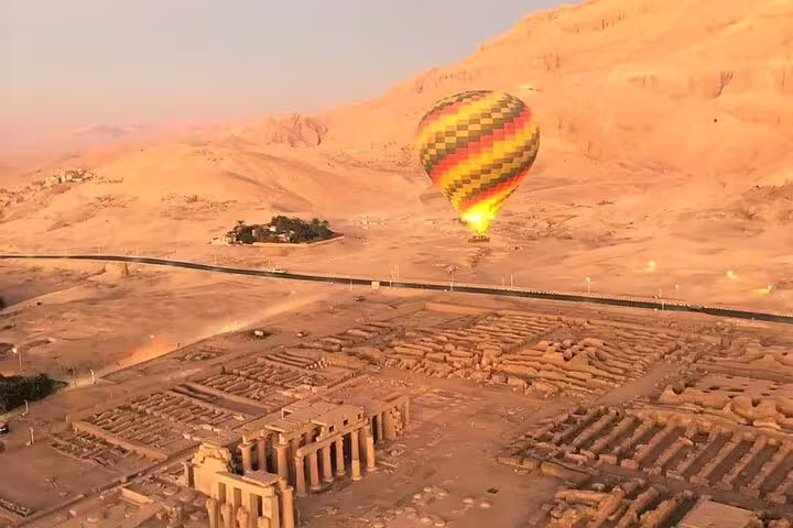 Sunrise Luxor hot air balloon ride over West Bank ruins and desert hills near ancient temples, Egypt