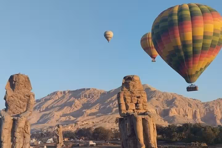Luxor hot air balloon ride over Nile River Valley with Colossi of Memnon and West Bank mountains at sunrise