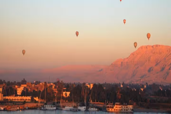 Sunrise hot air balloons floating over Luxor and the Nile River with desert hills, part of VIP balloon ride