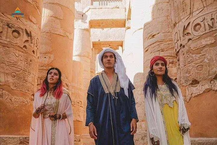 Travelers in traditional dress between Karnak Temple columns in Luxor, Egypt on full-day guided tour