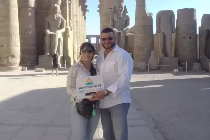 Travelers at Karnak Temple in Luxor beside giant statues, classic full-day tour of Luxor temples Egypt
