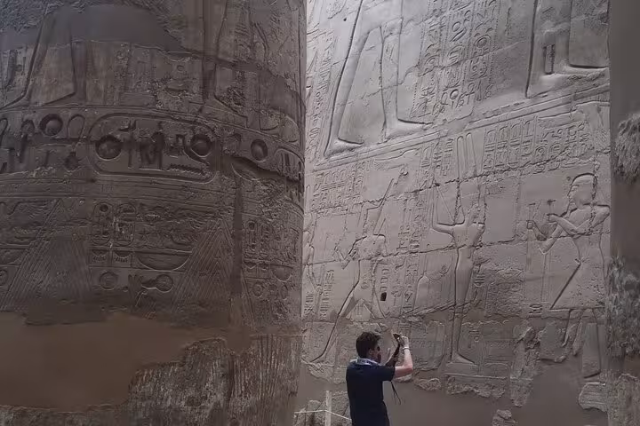 Traveler photographing ancient hieroglyphs at Karnak Temple, Luxor on private day trip from Hurghada