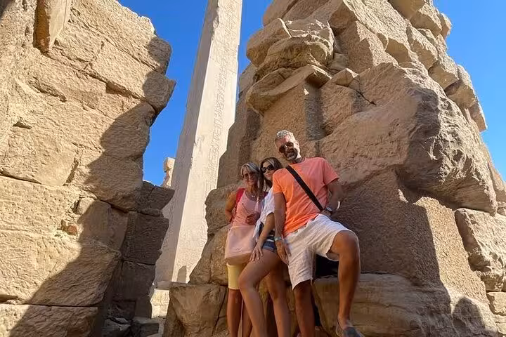 Private Luxor tour from Hurghada at Karnak Temple, tourists posing by towering obelisk and stone ruins