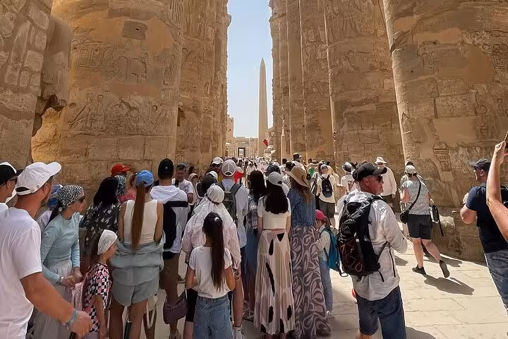 Tourists exploring the majestic Karnak Temple with its towering obelisks during a guided Luxor tour.